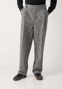 Pantaloni grigi ampi con tessuto strutturato e motivo sottile, dotati di tasche laterali e design a vita alta.