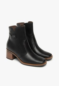 Schwarze Leder-Stiefeletten mit rundem Zehenbereich, mittelhohem Blockabsatz, seitlichem Elastexpaneel und einem dekorativen Riemen mit einer Metallakzent.