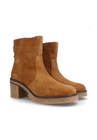 Botas de tobillo de ante marrón con tacón cuadrado, cremallera lateral y suela de goma texturizada. Presenta líneas limpias y un diseño minimalista.