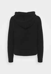 Sweat à capuche noir tricoté, manches longues, poignets et ourlet côtelés, présenté de dos sur un fond blanc uni.