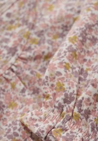 Blumenmusterstoff in Rosa-, Lila- und Gelbtönen, mit gerafftem elastischem Detail am Rand. Weiches, strukturiertes Baumwollmaterial.
