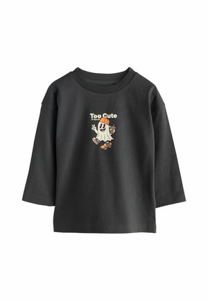 T-shirt noir à manches longues avec un fantôme de dessin animé sur un skateboard portant une casquette, tenant un verre, et un texte disant "Trop mignon pour effrayer."