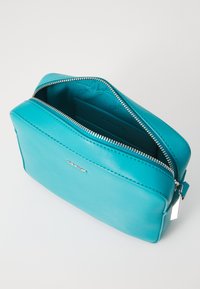 Turquoise leather cosmetic bag with a zippered closure, smooth texture, and a silver logo. Interior features additional pockets for organization.