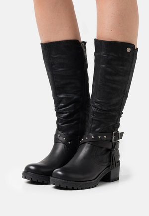 Bottes noires montantes en cuir souple, présentant un design décontracté, des accents de boucles et des clous, avec un talon épais et une semelle texturée.