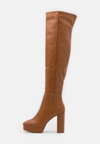 Bottes au-dessus du genou en faux cuir marron avec un bout carré, un talon épais et haut, et une finition mate lisse. Détails de couture sur la tige.