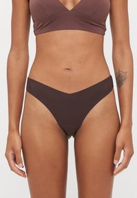 Parte inferior de bikini marrón con una cinturilla en forma de V. Hecha de una tela suave y elástica, con cobertura mínima y líneas limpias.