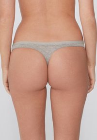String gris avec une texture lisse, présentant une taille douce et une couverture minimale, soulignant un design sans couture.