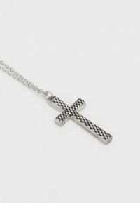 Sidabrinė kryžiaus pakabukas su tekstūruota, kryžminėmis linijomis, kabančiu iš plonos sidabrinės grandinėlės ant balto fono.