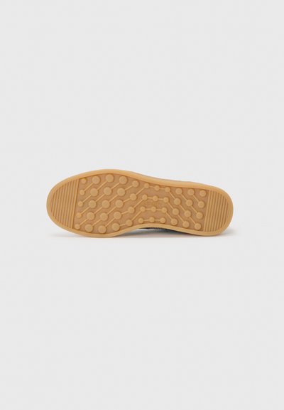 Rubber shoe sole with a textured surface featuring circular patterns and horizontal grooves; tan color with a smooth finish.