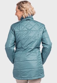 Türkisfarbene gepolsterte Jacke mit hohem Kragen und Rautenmuster. Sie hat eine taillierte Passform und eine weiche, glatte Textur.