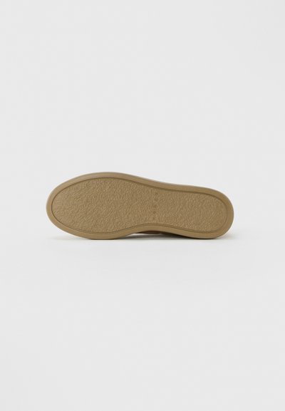 Light brown shoe sole with textured grip pattern, viewed from the bottom on a white background.
