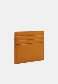 Porte-cartes en cuir jaune moutarde, présentant une surface texturée, quatre emplacements pour cartes et un design rectangulaire slim.