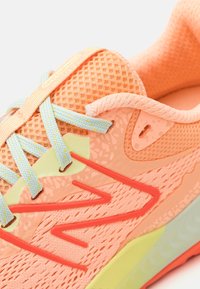 Chaussure de sport légère en corail avec tige en maille, lacets bleus et accents contrastants jaunes et oranges ; semelle en caoutchouc détaillée pour une meilleure adhérence.