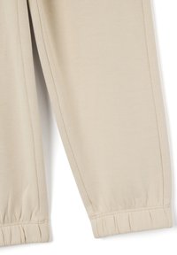 Beige sweatpants hebben een zachte textuur, elastische boorden en netjes gestikte naden, wat zorgt voor een ontspannen pasvorm met een strakke uitstraling.