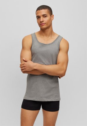 Graues Baumwoll-Top mit weitem Halsausschnitt und geradem Saum, getragen mit schwarzen Shorts. Der Stoff wirkt glatt und hat einen lässigen Schnitt.