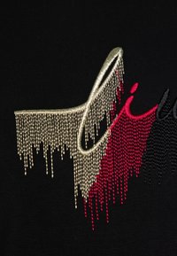 Tejido negro con un gran gráfico texturizado adornado con cristales de roca dorados, rojos y negros dispuestos en un patrón en cascada que forma la palabra "lit".
