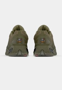 Para oliwkowych butów sportowych pokazanych z tyłu, z fakturowanymi podeszwami i okrągłymi logo Air Max na piętach.