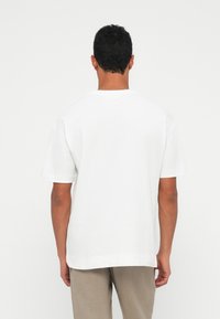 White cotton t-shirt with a relaxed fit, short sleeves, and a round neckline, featuring a plain design and hemmed edges.
