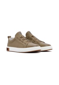 Zapatillas de cuero marrón con un acabado suave, suela de goma blanca y diseño con cordones. Presentan una puntera redondeada y un sutil logotipo en la lengüeta.