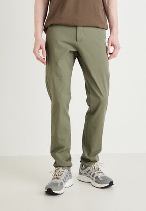 Pantaloni slim-fit verde oliva realizzati in tessuto leggero con una texture liscia. Caratterizzati da una vita a media altezza e tasche frontali.