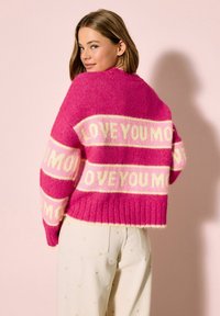 Púderrózsaszín, krémszínű csíkokkal díszített, körben levágott pulóver "LOVE YOU MORE" felirattal; bordázott alsó szegéllyel és puha tapintással.