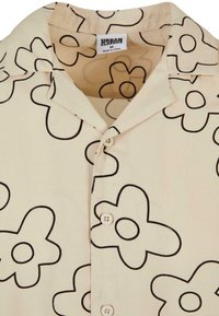 Beige košile na knoflíky s černými obrysy abstraktních květinových vzorů a sklopeným límcem, označená Urban Classics, velikost střední.