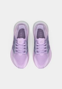 Des chaussures de sport violettes avec une tige en maille respirante, des détails texturés, trois rayures grises et une semelle amortie. "ULTRA BOOST" est embossé sur la languette.