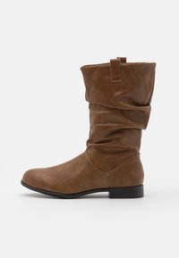 Botte hauteur genou en cuir synthétique marron avec un design décontracté, bout arrondi et petit talon noir. Dispose d'une boucle sur la tige pour faciliter l'enfilage.