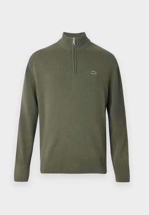 Olivgrüner Strickpullover mit einem halben Reißverschlusskragen, ribbelten Bündchen und Saum, mit kleinem Lacoste-Logo auf der linken Brust.