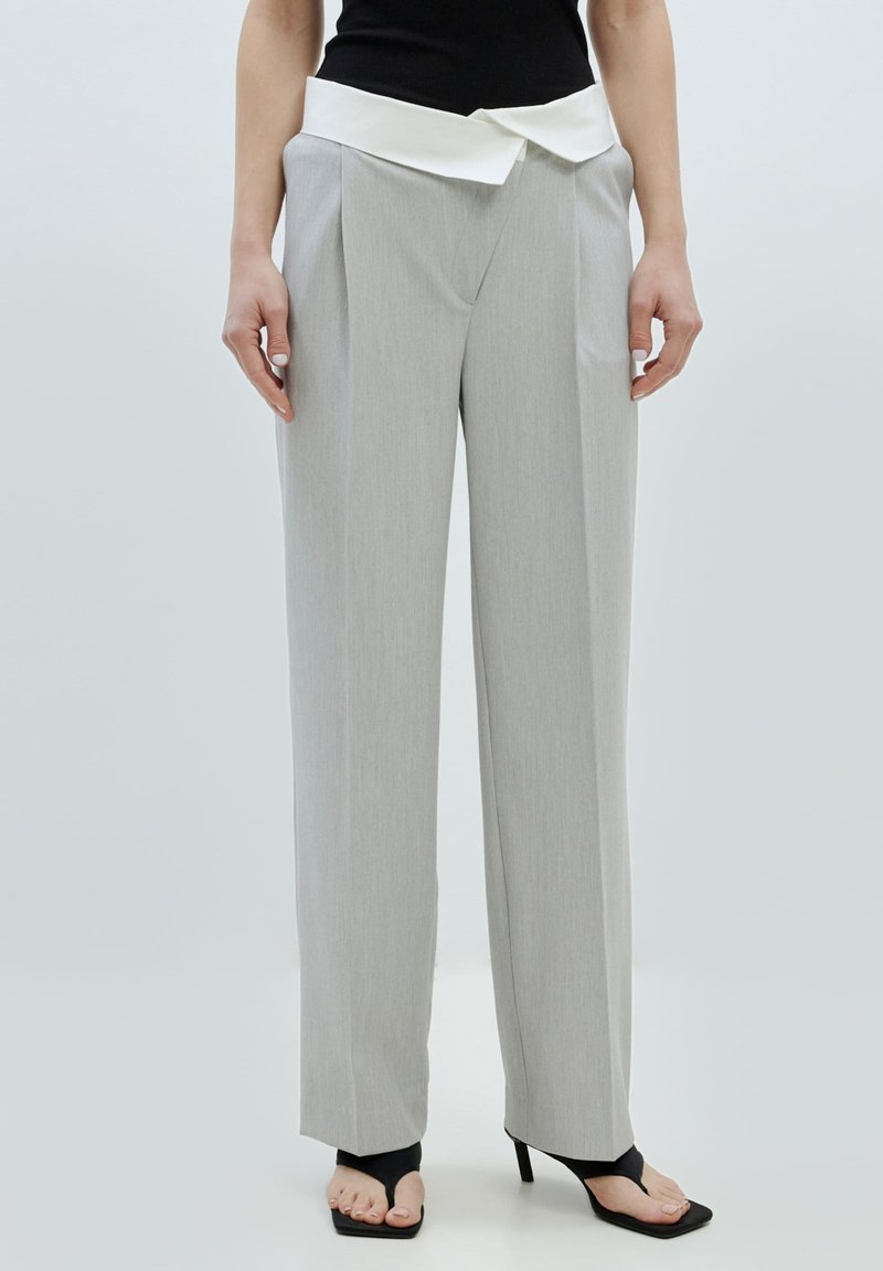 Helle graue weitgeschnittene Hose mit Vorderfalten und einem weißen umgeschlagenen Bund. Glatte Textur, maßgeschneiderter Schnitt und keine sichtbaren Muster.