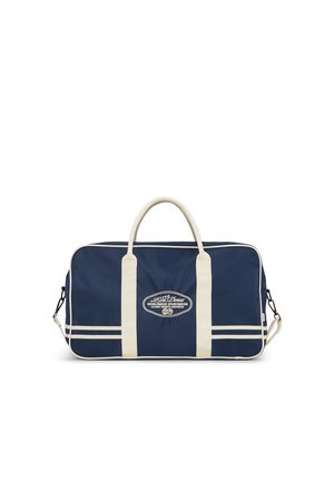 Navy blue and white sports duffel bag with double handles, a shoulder strap, and front logo reading "Worldwide Sportswear Classic Varsity Aesthetic."