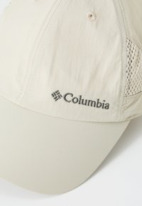Beige sapka ívelt billlel, hálós oldalsó panelekkel és hímzett "Columbia" logóval. Könnyű, légáteresztő anyagból készült.