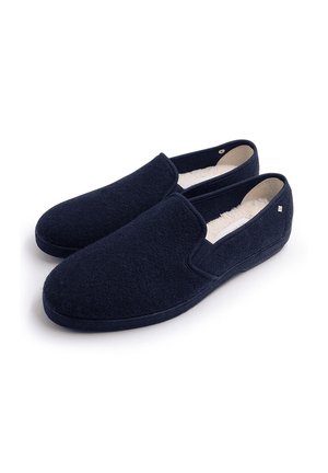 Chaussons bleu marine en feutre doux avec une doublure intérieure lisse. Design slip-on avec un bout arrondi et des accents minimalistes.