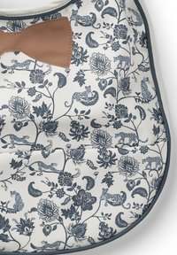 Blommönstrad kudde i vitt med blå design som föreställer leoparder och blommor, komplett med en brun läderrosett som accent.