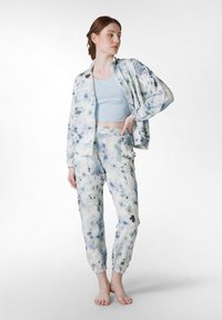 Trening floral ușor, în nuanțe de albastru deschis și alb, compus dintr-o jachetă cu fermoar și pantaloni cu manșete elastice, având un croi lejer și modele subtile.