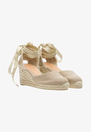 Wedges espadrilles beiges avec une tige en lin texturé, une plateforme en jute tressé et des liens de cheville en ruban. Design à bout rond et talon ouvert.