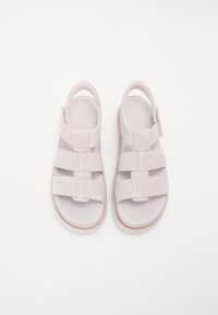 Lys lilla sandaler laget av myk semsket skinn, med flere brede stropper, bak støttende hæl og en teksturert såle.