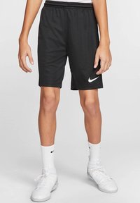 Svarta Nike träningstights med elastisk midja och vitt logotyp. Kombinerat med vita strumpor och skor, i ett andningsbart material.