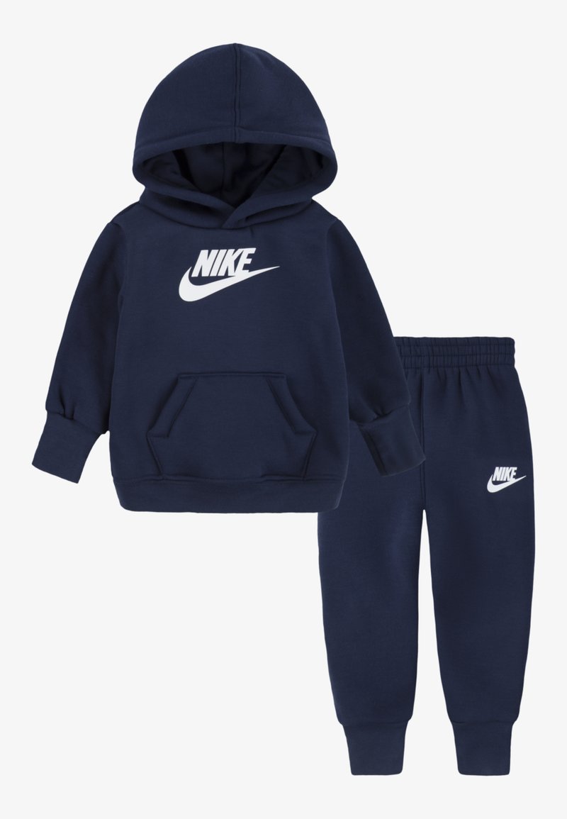 Completo felpa e pantaloni della tuta blu navy, realizzato in tessuto morbido. Presenta una tasca frontale e il logo Nike bianco su entrambi i pezzi.