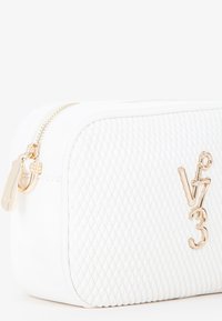 Pochette cosmetica bianca trapuntata con hardware dorato, dotata di chiusura zip e logo del brand in rilievo sulla parte anteriore. Forma rettangolare compatta.