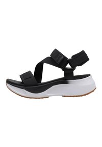 Sandalia negra con correas de tela ajustables, una plantilla acolchada blanca y una suela texturizada negra, que presenta un diseño deportivo y moderno.