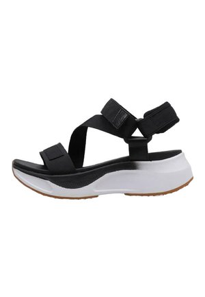 Sandalia negra con correas de tela ajustables, una plantilla acolchada blanca y una suela texturizada negra, que presenta un diseño deportivo y moderno.