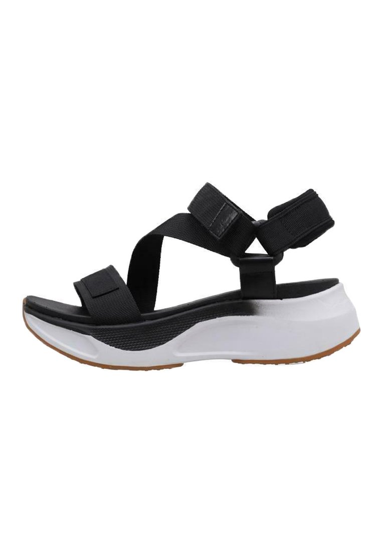 Sandalia negra con correas de tela ajustables, una plantilla acolchada blanca y una suela texturizada negra, que presenta un diseño deportivo y moderno.