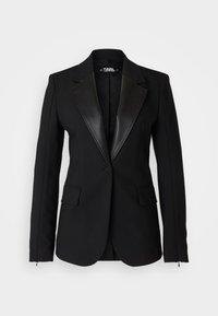 Czarna marynarka z satynowym szpiczastym kołnierzem, zapinana na jeden guzik, z dwoma przednimi kieszeniami oraz dopasowanymi długimi rękawami. Gładka tkanina o strukturalnym kroju.