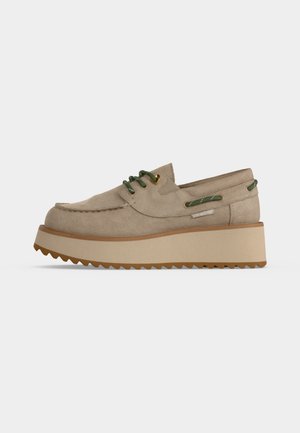 Beige ruskind platåsko med grønne snørebånd og kant, tyk rillede sål og mokkasinsyning.