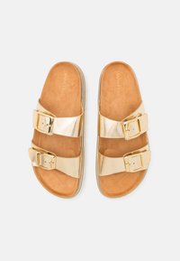 Gold-colored slide sandals with two buckle straps, a soft tan footbed, and a textured sole for grip. Smooth metallic finish and minimal design.