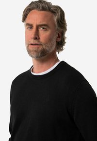 Mustat neulepaita, jossa on pyöreä kaula-aukko, ribbineuleiset hihansuut ja helma. Vasemmassa rinnassa on huomaamaton logokohta. Suuri sileä rakenne.