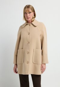 Beige wollen blend jas met een grote kraag, vijf knopen, twee voorkoeken en getextureerde manchetten. Soepele stof en een relaxte snit.