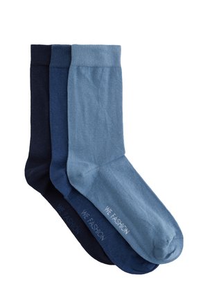 Trois paires de chaussettes courtes pliées en bleu clair, bleu moyen et bleu foncé, chacune avec le texte "WE FASHION" sur la semelle.