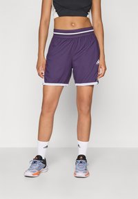 Pantaloni sportivi viola con bordini bianchi e una vita elastica a righe, realizzati in un materiale leggero, presentano un logo Adidas sulla gamba.
